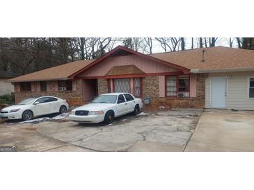 A charming single-story home with a brick facade, pink trim, and a well-maintained front yard at 1058 Viking Dr, Stone Mountain, GA 30083