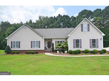 House exterior featuring beige vinyl siding, purple shutters, and a well-manicured lawn at 2204 Happy Hollow Se Ct, Conyers, GA 30094