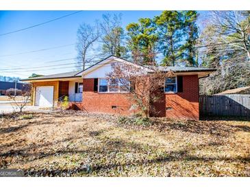 Brick ranch house with attached garage and mature trees at 653 Temple St, Lithia Springs, GA 30122