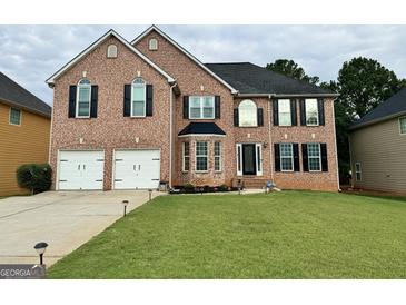 Brick two-story house with a two-car garage and landscaped lawn at 1122 Folkstone Dr, Mcdonough, GA 30253