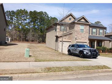Charming two-story home with a stone and siding facade, attached garage and police vehicle in the driveway at 284 Madison Grace Ave, Mcdonough, GA 30252