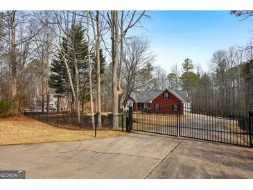 Brick house with gated entry, long driveway, and mature trees on a spacious lot at 55 Rainey Ridge Dr, Oxford, GA 30054