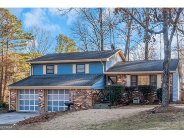 Ranch style home with brick and blue siding, two-car garage, and mature landscaping at 100 Traverse Ct, Atlanta, GA 30349