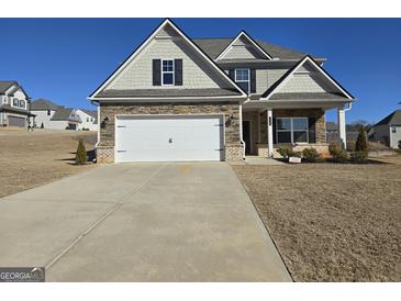 Charming home featuring stone accents, a two-car garage, and a well-manicured lawn at 1455 Weeping Tree Cir, Auburn, GA 30011