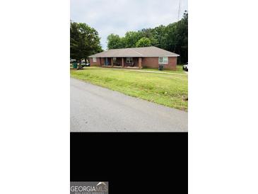 A single-story brick home with a lawn and a covered front porch at 241 E Ash St, Social Circle, GA 30025