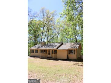 Charming ranch-style home featuring a cozy front porch, set amongst lush green trees on a sunny day at 1760 Upland Ridge Nw Dr, Conyers, GA 30012