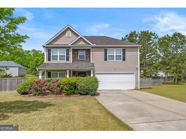 Charming two-story home featuring a manicured lawn, flower beds, and an attached two-car garage at 8264 Milam Loop, Fairburn, GA 30213