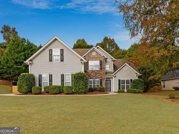 Charming two-story home featuring a combination of stone and vinyl siding, surrounded by mature trees and a well-maintained lawn at 228 Otter Cir, Fayetteville, GA 30215