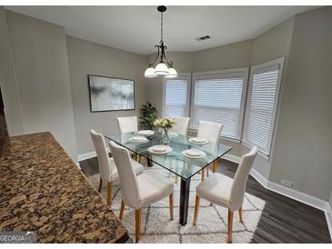 Bright dining room featuring a glass table, seating for six, and natural light from bay windows at 7214 Bedrock Cir, Lithonia, GA 30038