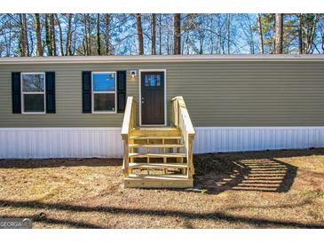 Mobile home exterior features a green facade, steps, and landscaping at 1979 Cardell Rd # 20, Austell, GA 30168
