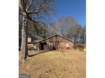 Charming single-story home with brick accents, surrounded by mature trees and a well-maintained front lawn at 8463 Alden Dr, Riverdale, GA 30274