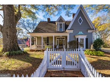 Charming two-story home with a welcoming front porch, landscaped yard, and a classic white picket fence at 86 Victoria Dr, Moreland, GA 30259