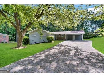 Charming single-story home with a long driveway and a covered carport surrounded by mature trees and lush greenery at 3403 Dodson Ter, East Point, GA 30344