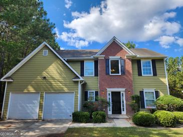 Two-story home with brick and siding, features an attached two-car garage and manicured landscaping at 5725 Cedar Pass, Fairburn, GA 30213