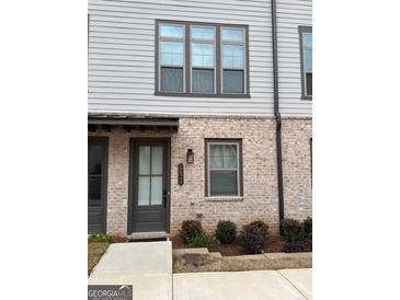 Charming townhouse with a gray brick facade, a dark front door, and well-maintained landscaping at 2624 Caruso Way, Atlanta, GA 30339