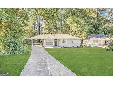 Charming single-story home with a well-manicured lawn and covered carport surrounded by lush green trees at 1785 San Gabriel Ave, Decatur, GA 30032