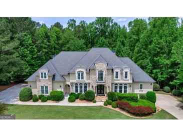 Stately home featuring stone and stucco exterior, lush landscaping, and a circular driveway at 709 Prestige Pt, Peachtree City, GA 30269