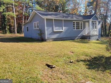 Charming single-story home features blue siding, a grey roof, and a well-maintained front yard at 4418 Sims Rd, Ellenwood, GA 30294