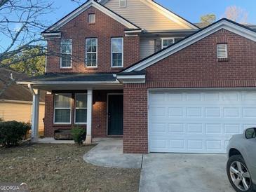 Traditional brick home featuring a two-car garage, covered porch, and well-maintained landscaping at 5620 Sable Way, Atlanta, GA 30349