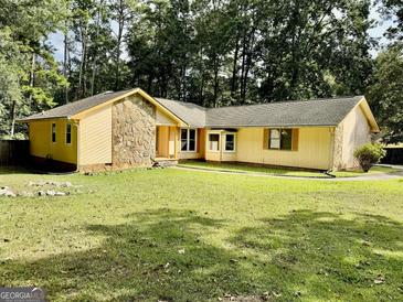 Charming yellow ranch-style house with stone accents and a lush green lawn, surrounded by mature trees at 1327 Highway 54 E, Fayetteville, GA 30214