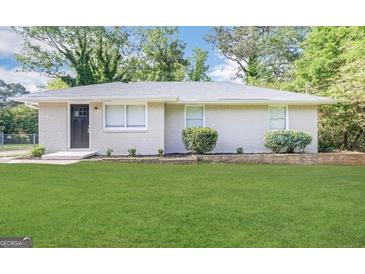 Charming one-story brick home with a well-manicured green lawn and landscaped garden bed at 3711 Tulip Dr, Decatur, GA 30032