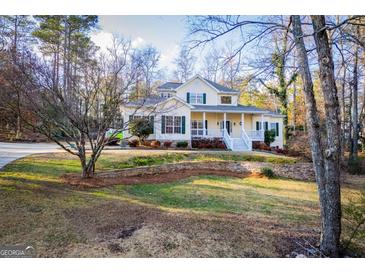 Charming two-story home boasts a welcoming front porch and beautifully landscaped front yard at 7364 N Mitchell Ct, Villa Rica, GA 30180