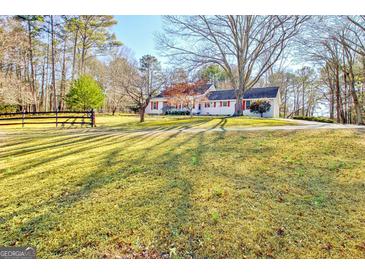 Expansive front yard with a charming single-Gathering home, surrounded by mature trees and a wooden fence at 125 Keyland Dr, Fayetteville, GA 30215