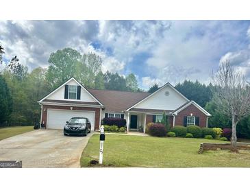 Charming single-story home featuring a manicured lawn, brick accents, and an attached two-car garage at 25 Prince Edward Way, Covington, GA 30016