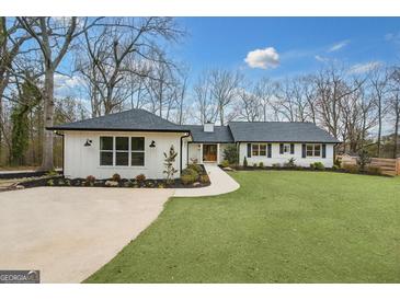 Charming single-story home featuring a well-manicured lawn, black roof, and a welcoming walkway at 757 Fischer Rd, Sharpsburg, GA 30277