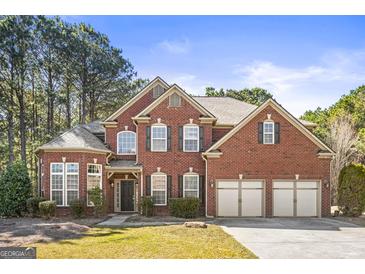 Stunning red brick home featuring a three car garage, manicured lawn, and mature trees at 100 Windmeadow Way, Fayetteville, GA 30214