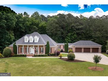 Stately brick home boasts a manicured lawn, attached three-car garage and a welcoming front porch at 401 Robinson Rd, Peachtree City, GA 30269