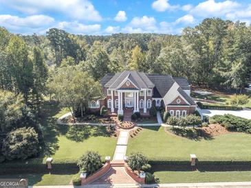 Magnificent brick home with manicured lawn, mature trees, and a grand entrance with stately white columns at 125 Turnberry Cir, Fayetteville, GA 30215
