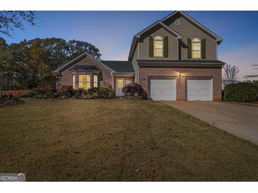 Charming two-story home with brick accents, two-car garage, and well-manicured lawn at dusk at 1022 Gloria Grand Blvd, Mcdonough, GA 30252