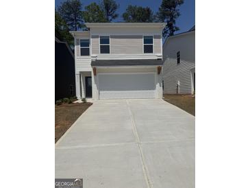 Two-story home featuring a two-car garage, a dark front door, and a long concrete driveway at 4856 Station Ln # 21, Union City, GA 30349