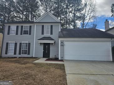 Two-story home featuring gray siding, black shutters, a white garage door, and a well-manicured front yard at 6558 Eastbriar Dr, Lithonia, GA 30058