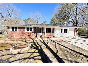Charming brick home featuring a well-maintained front yard with a circular fire pit and spacious driveway at 1209 Topaz Ln, Villa Rica, GA 30180
