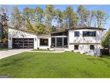 Contemporary home featuring a lush front lawn, dark framed windows, and a two-car garage at 4217 Paces Ferry Se Rd, Atlanta, GA 30339