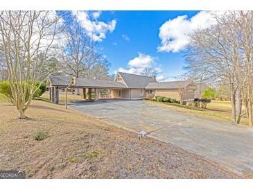 Sprawling home with a large driveway and unique covered parking area, set against a blue sky at 240 Sandy Lake Cir, Fayetteville, GA 30214