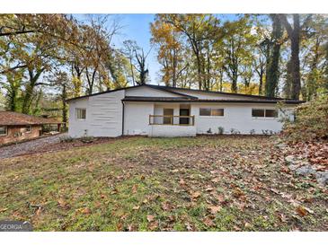 Charming white brick home featuring black trim and mature trees at 2544 Overlook Dr, East Point, GA 30344