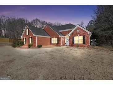 Charming brick home featuring a manicured lawn, black shutters, complemented by warm lights in a tranquil neighborhood at 1855 Wakefield Trce, Mcdonough, GA 30252