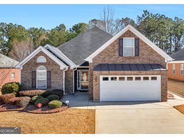 Charming brick home featuring a two-car garage, well-maintained landscaping, and classic architectural details at 509 Carleton Pl, Locust Grove, GA 30248
