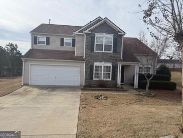 Two-story home featuring stone accents and a two-car garage on a well-manicured lawn at 1631 Royal Ives Dr, Lawrenceville, GA 30045