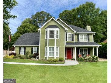 Charming two-story home features a manicured lawn, red front door, and a welcoming front porch at 642 Grecken Grn, Peachtree City, GA 30269