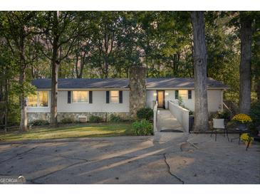 Charming single-story home with a stone chimney, wooden wheelchair ramp, and mature trees at 4226 Highway 155 N, Stockbridge, GA 30281