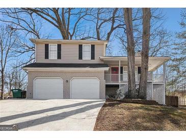 Charming two-story home with a two-car garage, brick accents, covered porch, and mature trees at 3822 Holland Dr, Snellville, GA 30039
