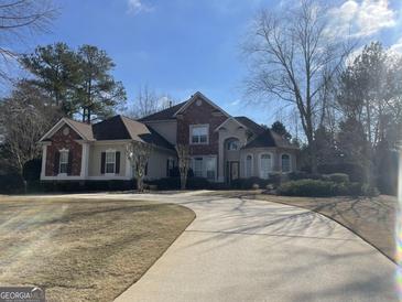 Stunning two-story home featuring a blend of brick and stucco, accented by an inviting curved driveway and manicured landscaping at 612 Champions Dr, Mcdonough, GA 30253