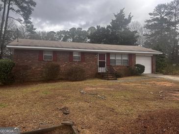 Charming one-story brick home featuring an attached garage and a well-maintained front yard at 103 Emory Way, Oxford, GA 30054