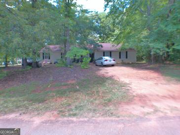 Charming one-story home featuring neutral siding, dark shutters, and a neatly maintained front yard with mature trees at 255 Countryside Ln, Covington, GA 30016