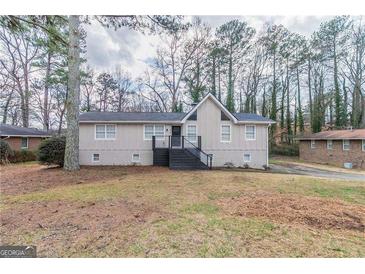 Charming home featuring a gabled roof, black deck, and brick foundation, nestled in a wooded landscape at 4565 Tudor Castle Dr, Decatur, GA 30035