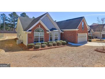 Charming home featuring a brick and siding exterior, complemented by mature landscaping and a well-manicured lawn at 227 Lantana Dr, Locust Grove, GA 30248